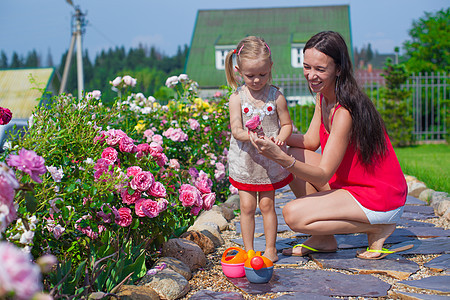 年轻母亲和她可爱的女儿 在花园的花朵旁边孩子幸福公园成人拥抱父母微笑女士家庭童年图片