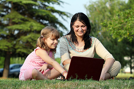 公园内携带手提笔记本电脑的女童和孩童图片