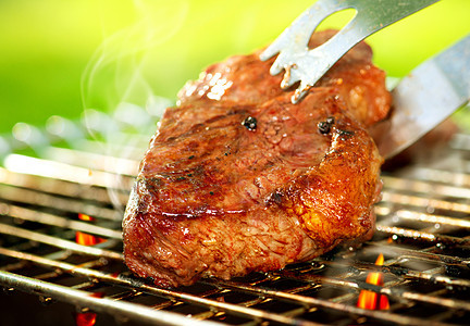 在BBQ上喷出一个牛排的火焰野餐生物家庭牛肉餐厅烧伤炙烤木炭烹饪派对图片