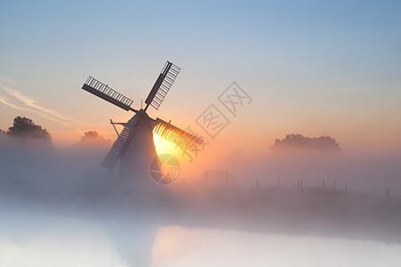 浓雾中的荷兰风车风景季节蓝色阳光天空薄雾反射橙子太阳农田图片