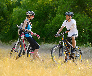 快乐的年轻夫妇在山边骑车假期男人微笑幸福自行车娱乐女孩闲暇头盔冒险图片
