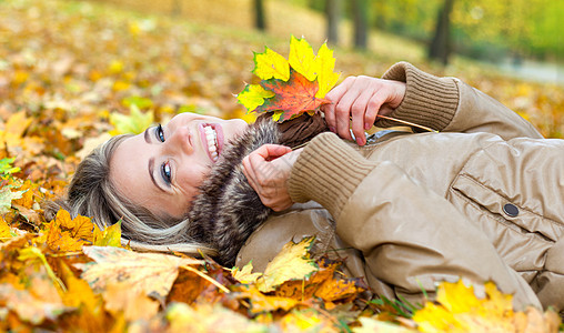 秋天 年轻微笑的女子躺在树叶上图片