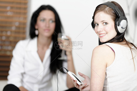 听音乐的两位朋友耳机椅子沙发八卦酒精说谎歌曲女士微笑休息室图片