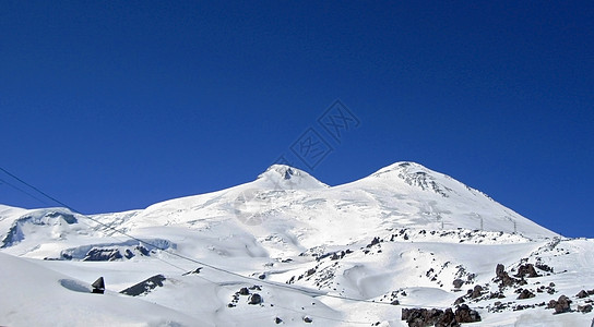 雪下和清空下的高加索山脉蓝色顶峰山脉石头双胞胎天空季节爬坡运动山峰图片