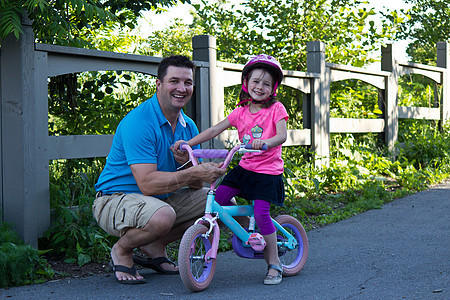 儿童学习与父亲一起骑自行车青年帮助孩子男性运动女孩爸爸童年家庭踏板图片