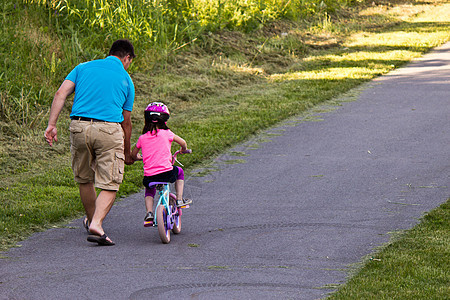 儿童学习与父亲一起骑自行车踏板青年童年家庭帮助运动爸爸两个人公园女孩图片