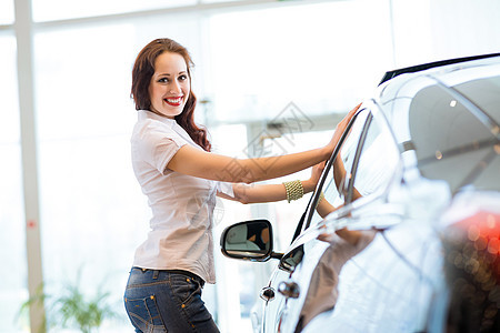 站在汽车旁边的年轻妇女客户协议经销商服务兜帽女士男人合同发动机车库图片