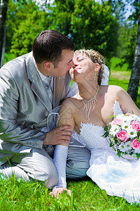 结婚夫妇坐在草吻上图片