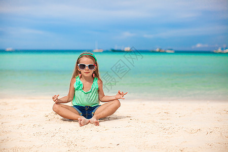 美丽的小女孩坐在异国海滩上的莲花沙滩上海滨假期海洋童年孩子头发女孩女性支撑情调图片