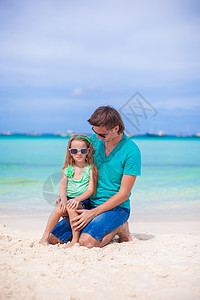 年轻父亲和他的小女儿坐在热带白色沙滩上幸福爸爸海洋男性海岸海岸线海滨情调异国父母图片