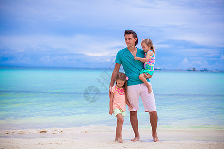 年幼的父亲和两个小孩在海边散步婴儿假期乐趣成人女儿情调海岸海洋家庭男性图片