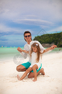 年轻父亲和他的小女儿坐在热带白色沙滩上情调异国家庭女士爸爸孩子幸福乐趣男人海岸图片