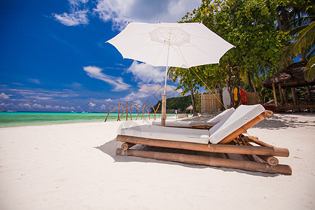 拥有雨伞和沙椅的热带空沙滩平地天堂景色情调旅行海岸线天蓝色海滩休息室蓝色椅子异国晴天图片
