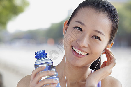 喝瓶装水的年轻女子聆听音乐冷饮长发生活方式喜悦听力耳机服装运动员享受摄影图片