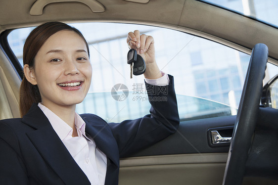 女商务人士坐在汽车中 展示钥匙 车辆内车马尾辫驾驶玻璃摄影反射人士沟通内饰手机公司图片