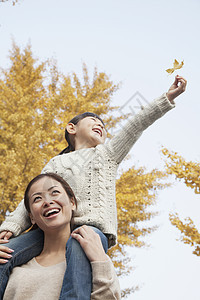 女儿骑着小猪背坐在母亲的肩上享受秋季假期收腰摄影妈妈团结乐趣家庭快乐衣物活动情绪图片