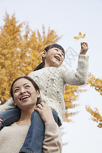 母亲和女儿享受秋天的公园保暖摄影孩子树区女性黑发快乐女孩们毛衣家庭图片