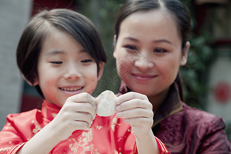 母亲和女儿在传统衣服中做面条 紧闭起来喜悦饮食饺子幸福马尾辫女孩们两个人摄影微笑面团图片