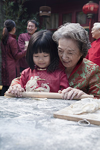 外祖母和孙孙孙孙孙孙女用传统衣服做面团白发父亲老年微笑教学滚动饺子童年女儿母亲图片