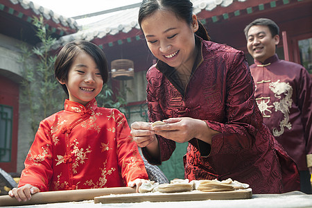 母亲和女儿在传统服装中做面子三个人摄影孩子童年微笑面团收腰幸福饺子饮食图片