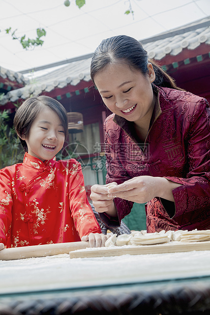 母亲和女儿在传统服装中做面子文化孩子棕色幸福马尾辫微笑乐趣女孩们面团团结图片