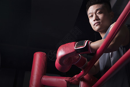 男性拳击手的肖像 在环边休息肘部 看着摄像机 低角度视线图片