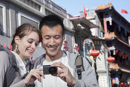 年轻夫妇观光 看数字摄影机游客摄影闲暇旅行团结水平异性恋年轻人微笑文化图片