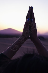 在中国的沙漠中 双手合十祈祷的宁静年轻女子举过头顶 特写图片