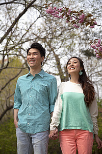 快乐笑笑的年轻夫妇 在春天在公园手牵手 长3/4宽图片