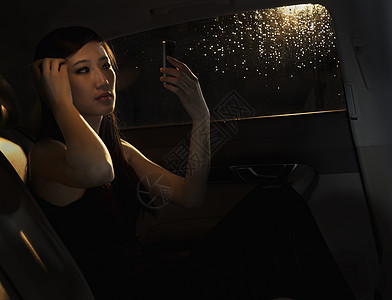 北京雨夜出门前 年轻女子坐在车里 用手机检查头发图片