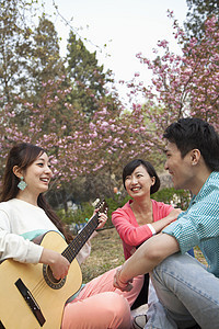 年轻快乐的朋友们在春季公园里玩吉他 弹吉他图片