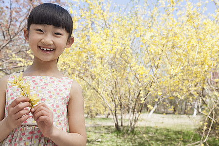 春天在公园里 拿着一朵黄花的微笑女孩的肖像图片