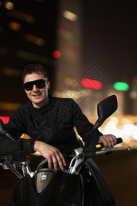 在北京晚上坐在摩托车上 戴着太阳眼镜微笑的年轻男人在北京图片