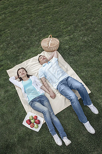 几个躺在野餐毯子上两个人公园微笑饮食篮子团结幸福活动夫妻摄影图片