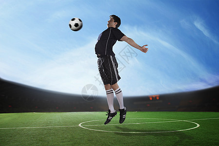 足球选手在体育场用胸膛打球 白天打球图片