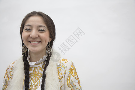 身着哈萨克斯坦传统服装 工作室拍摄的布丁的年轻微笑妇女肖像头发幸福影棚耳环活力辫子身份摄影裙子女性图片