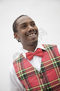 身穿格斗背甲和红领领结的年轻人肖像 摄影棚拍摄种族幸福短发微笑格子纽扣活力倾斜衬衫文化图片