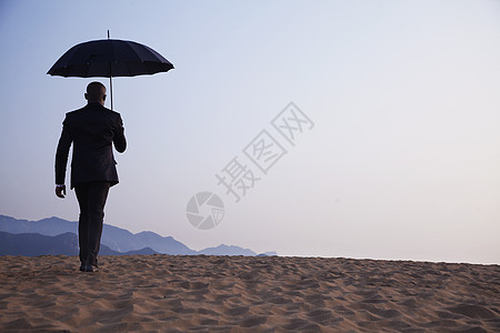 商务人士拿着雨伞 在沙漠中走远了 (笑声)图片