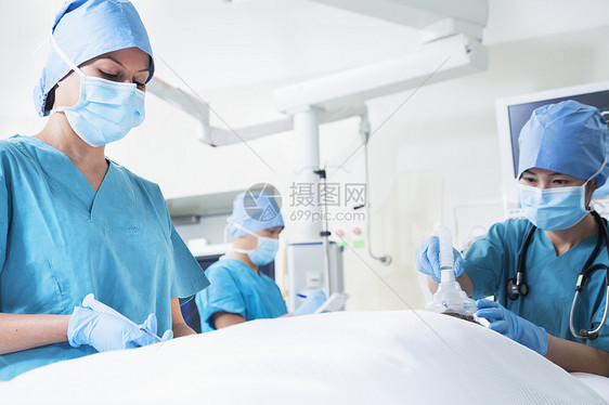 外科医生小组与一名躺在手术台上的病人一起工作图片