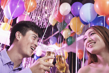 两个朋友庆祝 与香槟敬酒 在北京的夜总会 在背景中的气球图片