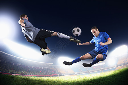 两个中空足球运动员踢足球球 晚上在体育场的灯光下打背景图片