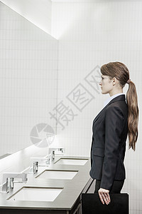 长头发的年轻女商务人士对着镜子看着镜子 在浴室里准备自己的工作图片