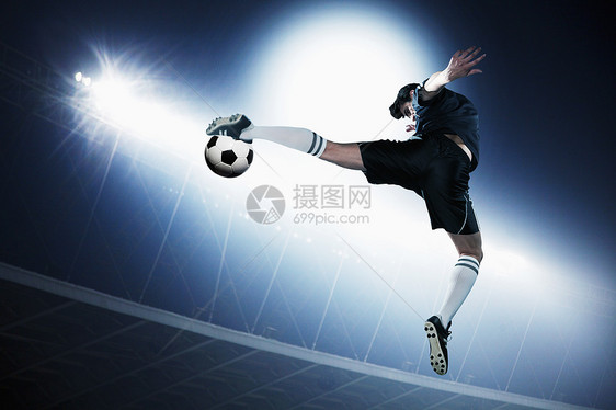 足球选手在空中中空踢足球球 晚上打体育场的灯背光竞赛战略斗争成就专注足球服运动足球场逆境图片