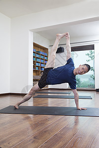 在瑜伽工作室做瑜伽的男人举起双腿 伸展手臂图片