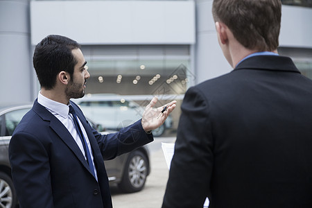 汽车销售员持有车钥匙 向一名青年商务人士出售一辆车图片