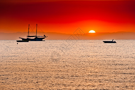 海和海的山后面有红色的日落图片