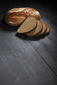 木制桌上的切黑面包木板化合物大麦桌子粮食棕色黑色营养收获杂货店图片
