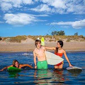 快乐的青少年冲浪者在海滩岸边聊天派对男性运动海滨团体幸福冲浪板冲浪木板比基尼图片