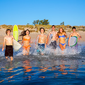 青少年冲浪者团体在海滩上喷水海洋女性蓝色派对假期女孩们冲浪海滨自由波浪图片
