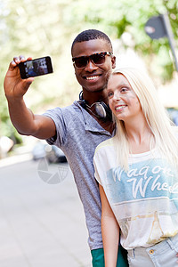 年轻笑笑多种族的情侣 用智能手机接着foto幸福摄影相机女士女孩男性电话假期照片朋友们图片